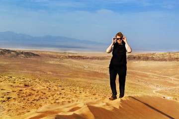 Footprints and man looking at the view at the top of a dune