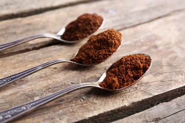 Spoons with coffee on wooden table, close up