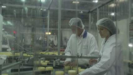  Quality control workers in pharmaceutical factory inspect medical or cosmetic containers on production line. Manufacturing business industry and cosmetic packaging firm