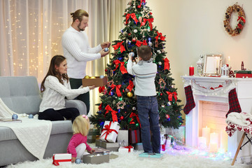 Family decorating Christmas tree in home holiday living room