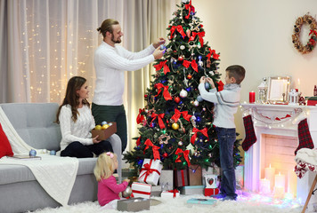 Family decorating Christmas tree in home holiday living room