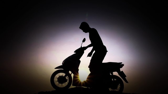Man starts driving a motorcycle, silhouette