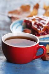 Cup of tea with autumn decor on wooden table.