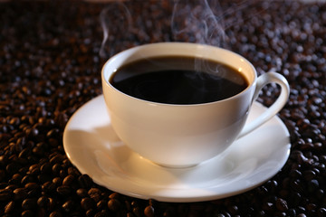 Cup of hot coffee on coffee beans background