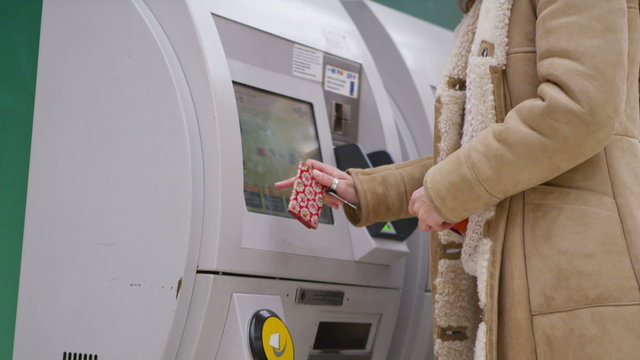  young attractive female purchasing train ticket from machine