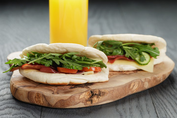 rustic sandwiches with ham arugula and tomatoes in pita bread on wood table