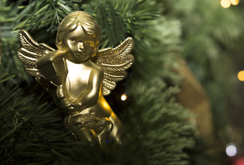 Christmas tree decorated with toys. Yellow angel hanging on a branch of a Christmas tree.