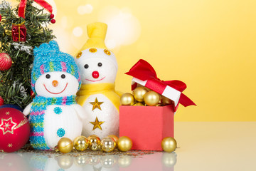 Little snowmen and Christmas decorations close-up on a yellow ba