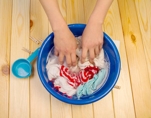 Women's hands wash clothes in blue pelvis