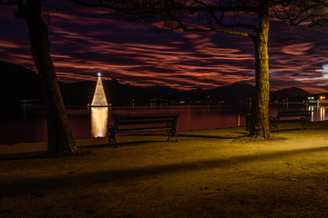 Christmas tree on Lake Woerthersee during colorful sunset. Austria, Carinthia .