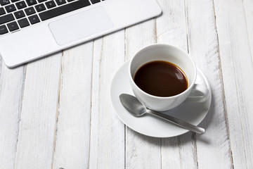 Laptop and coffee on white wooden table. View from above