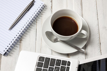 Coffee and laptop, notepad with pen on wooden table. View from above