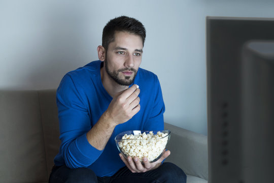 Man eating popcorn watching television 