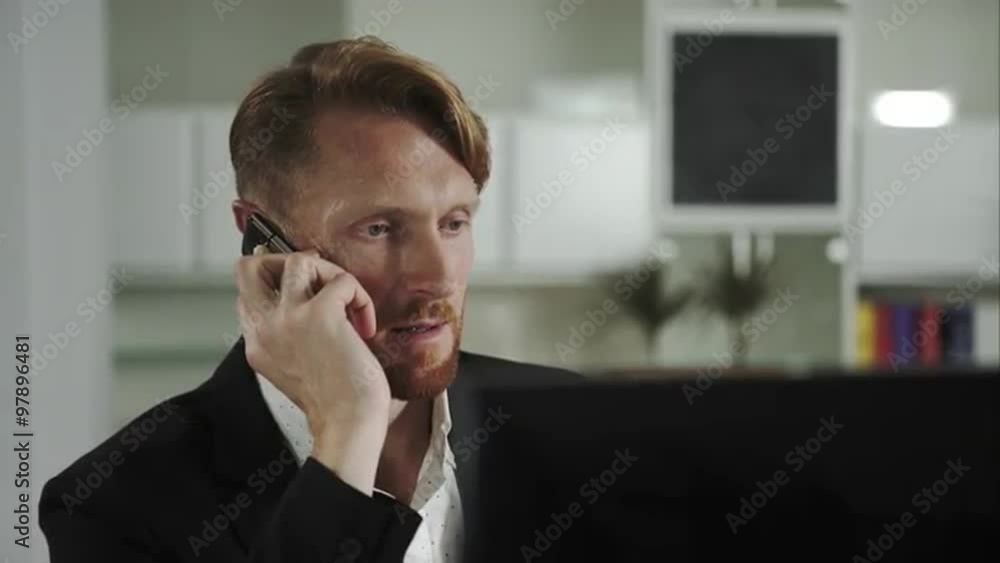 Poster Red-haired man sitting at a computer and calling on the phone