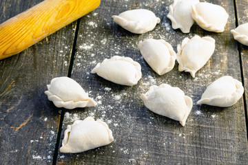 Raw dumplings with potatoes and onions on dark wooden table