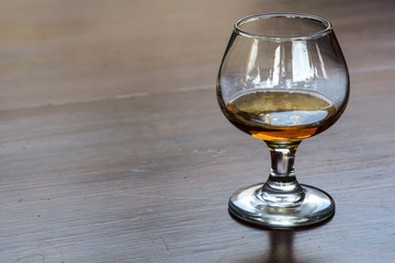 Glass of aged tequila on a shiny wooden surface