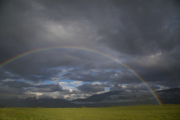 Beautiful mountain valley rain storm over hay field with a rainb