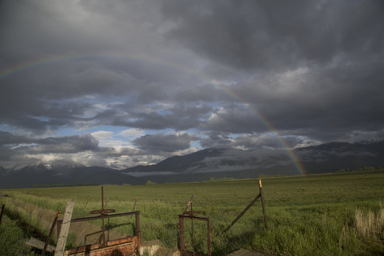 Summer storm with a rainbow over a mountain valley field