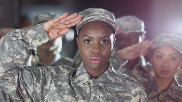  Mixed ethnicity female soldiers stand to attention and salute. 