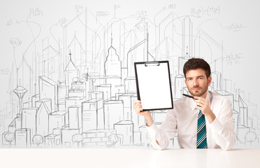 Businessman sitting at the white table with hand drawn buildings