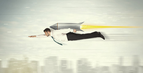 Superhero business man flying with jet pack rocket above the cit