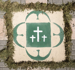 three white crosses painted on the floor on a square with herbs
