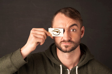 Young person holding paper with angry eye drawing