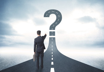 Business person lokking at road with question mark sign