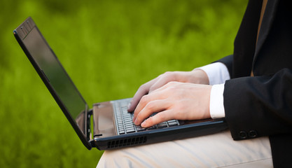 Businessman pressing modern laptop computer on colorful backgrou