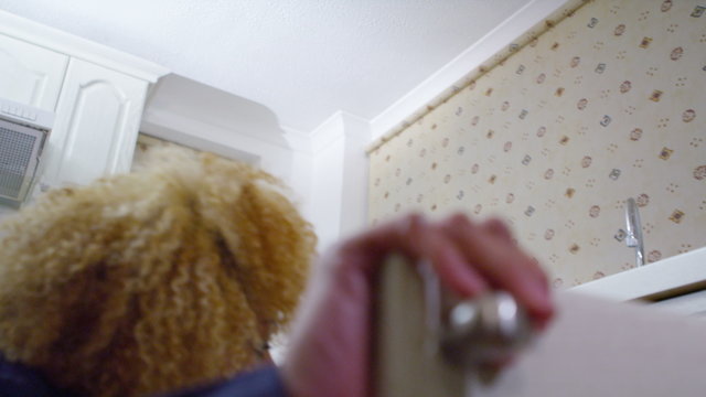  Female plumber at work trying to fix a problem underneath domestic kitchen sink.