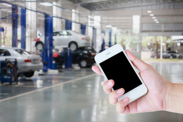 hand hold smartphone with auto tire repair services blurred back