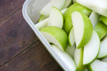 Fruit in plastic box with a wooden floor in the background.