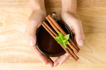 Cup of hot chocolate or cocoa hold by hand on wooden background