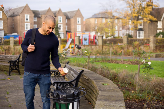 man throwing rubbish in the bin in a park