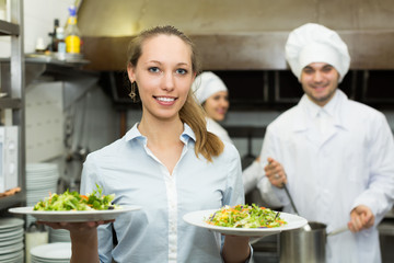 Chefs and waitress at kitchen