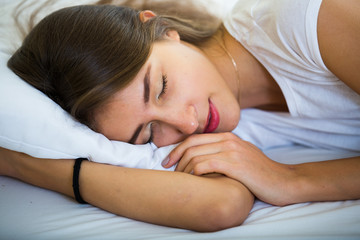 Young female lying with closed eyes in bed