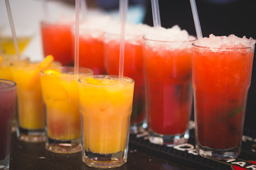 Beautiful row line of different colored alcohol cocktails with mint on a christmas party, martini, vodka with bubbles, wine and others on decorated catering bouquet table on open air event, picture 