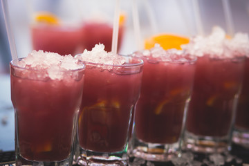 Beautiful row line of different colored alcohol cocktails with mint on a christmas party, martini, vodka with bubbles, wine and others on decorated catering bouquet table on open air event, picture 