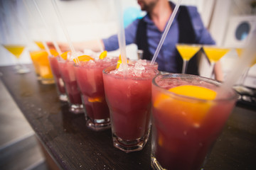 Beautiful row line of different colored alcohol cocktails with mint on a christmas party, martini, vodka with bubbles, wine and others on decorated catering bouquet table on open air event, picture 