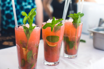 Beautiful row line of different colored alcohol cocktails with mint on a christmas party, martini, vodka with bubbles, wine and others on decorated catering bouquet table on open air event, picture 
