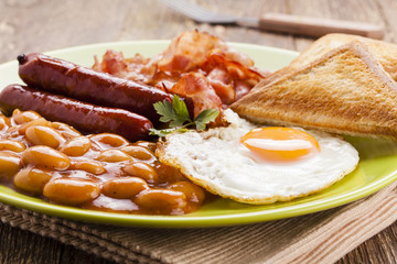 Full english breakfast with bacon, sausage, fried egg, baked bea