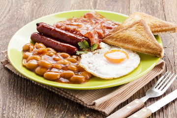Full english breakfast with bacon, sausage, fried egg, baked bea