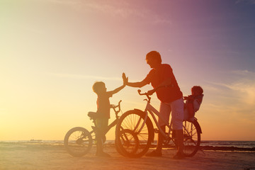 Fototapeta na wymiar Biker family silhouette, father with two kids on bikes