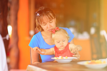 mother feeding little daughter in cafe