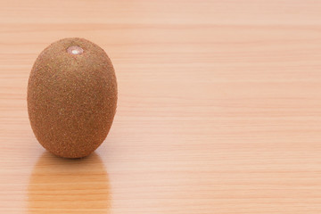 One kiwi fruit on the wooden table.