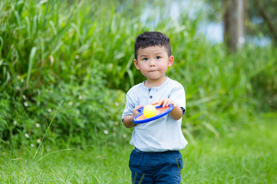 Asian Kid Playing Tennis Ball At Park