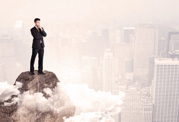 Happy businessman standing on stone top