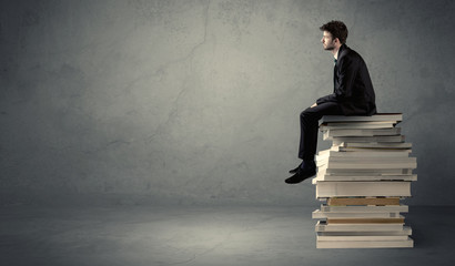 Stylish male seated on books