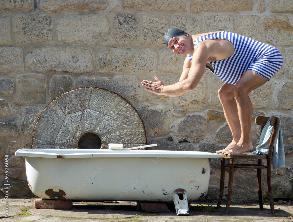 Wall mural man in retro swimsuit jumps to the outdoor bathtub