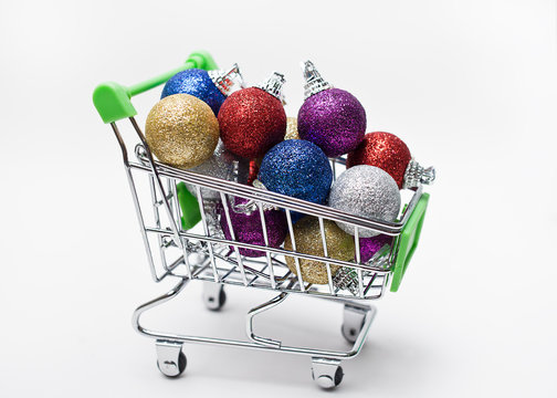 Colorful Christmas balls in a shopping cart on white background
